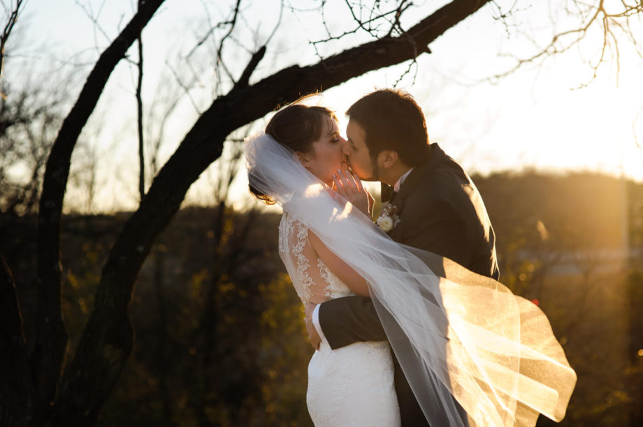 bride groom kissing sunlit veil portrait